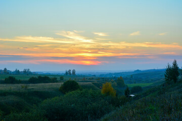 Fototapeta premium Sunset with blue and orange clouds over a Rolling Valley Landscape