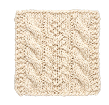 A square swatch of thick cream colored wool yarn featuring a classic cable knit stitch pattern