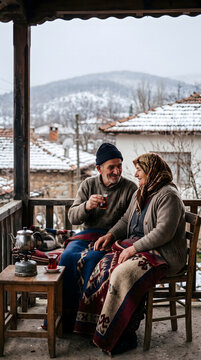 Older Turkish couple sharing hot tea together on a rural porch in winter