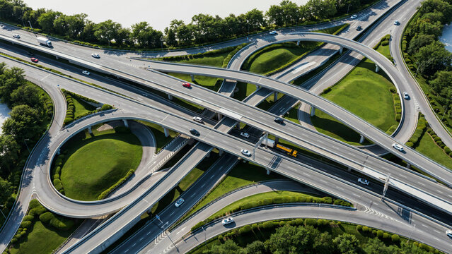 Aerial view of a complex highway junction with circular ramps and cars driving through forest