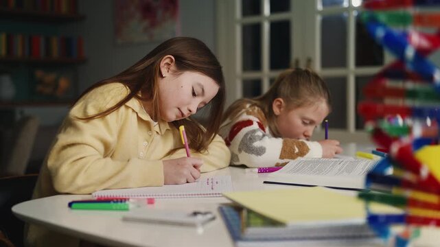 Two diligent siblings write in notebooks while doing homework together