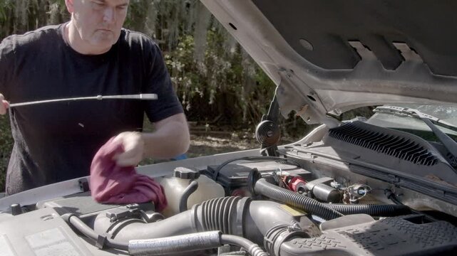 A mechanic checks the engine oil in a large 8 cylinder diesel engine.