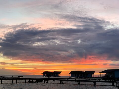GORONTALO, INDONESIA - SEP 25, 2021: Stunning sunset with colorful clouds over water bungalows and wooden pier at Pulo Cinta