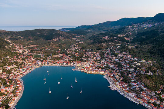Aerial view of Ithaca town nestled in a bay with sailboats and traditional buildings surrounded by lush green hills in Ithaki, Greece.