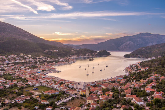 Aerial view of Vathy, the main port of Ithaca, with its traditional houses, boats anchored in the bay, and surrounding hills at sunset in Ithaki, Greece.