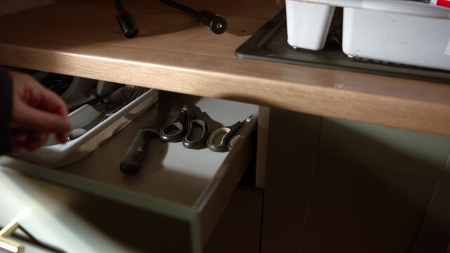 Hand opening green kitchen drawer and gets knife