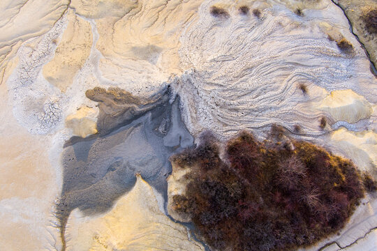 Aerial view of the Mud Volcanoes of Paclele Mari, showcasing unique grey mud formations, cracked earth patterns, and sparse vegetation in Paclele, Buzau County, Romania.
