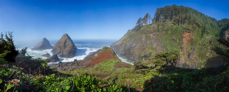 Beautiful wide panoramic view of a wild rocky ocean coast with green mountains and sea stacks at sunny day
