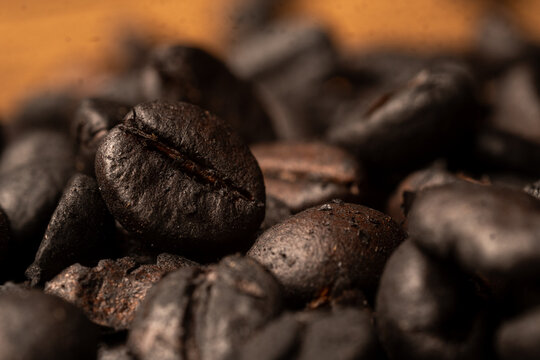 Extreme macro close up shot of dark roasted coffee beans surface texture with selective focus and shallow depth of field for coffee background.
