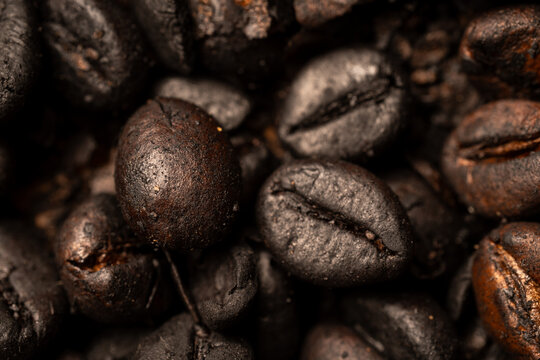 Extreme macro close up shot of dark roasted coffee beans surface texture with selective focus and shallow depth of field for coffee background.
