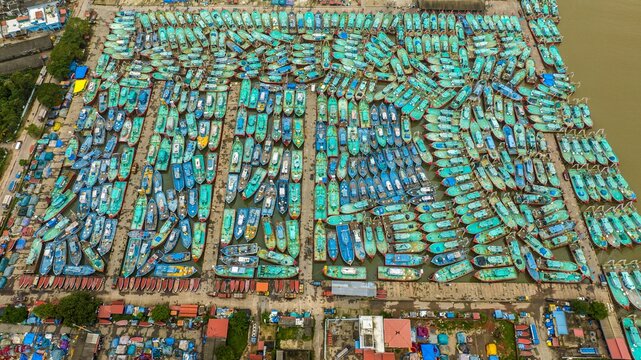 Aerial view of Malpe Fishing Harbour with hundreds of colorful fishing boats docked in rows, creating a vibrant pattern on the water in Udupi, Karnataka, India.