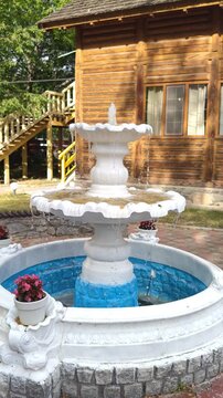 An old white fountain with falling water in a park.