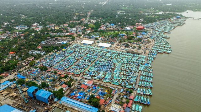Aerial view of Malpe Fishing Harbour with hundreds of colorful fishing boats docked in the harbor, surrounded by coastal infrastructure and lush greenery in Udupi, Karnataka, India.