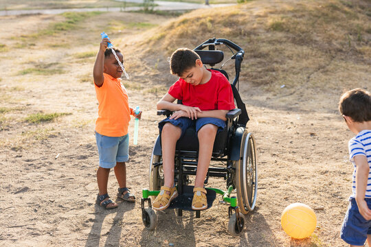 Children playing bubbles with boy in wheelchair