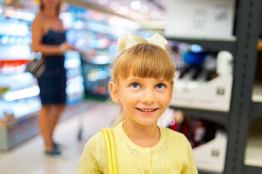 Young ukrainian girl smiling, shopping for food with mother in a spanish supermarket