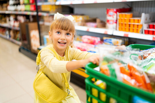 Happy child pushing a full shopping cart, enjoying a family outing in the grocery store