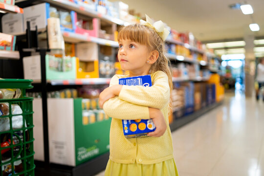 Young girl holding cookies while shopping with family in a supermarket aisle