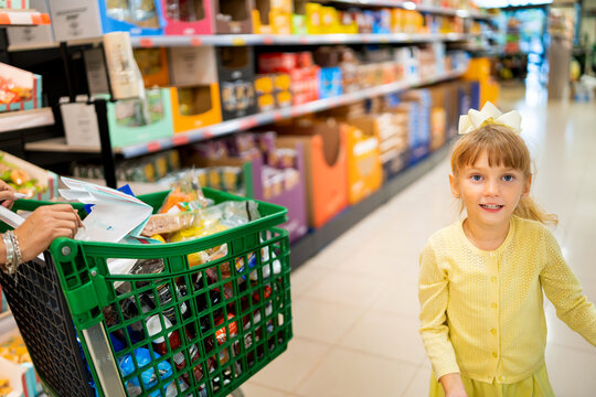 Ukrainian mother and young daughter grocery shopping in spanish supermarket