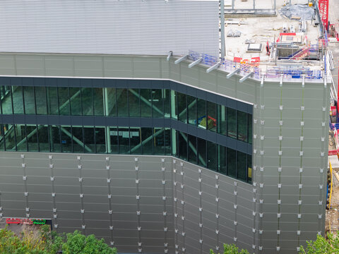 Aerial view of a modern data center under construction featuring a sleek glass and metal facade with visible structural steel beams and rooftop work areas in the United Kingdom.