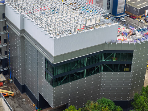 Aerial view of a modern data center under construction with a steel frame roof, glass facade, and metal cladding in the United Kingdom.