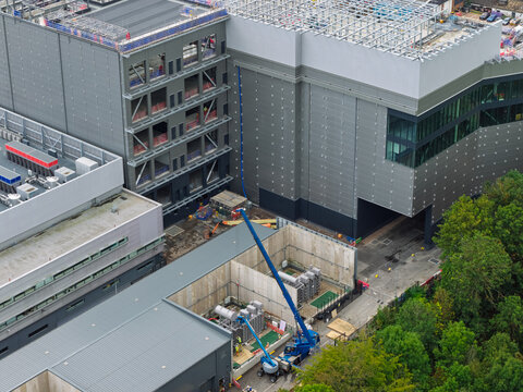 Aerial view of a large data center construction site with industrial buildings, a blue crane, and technical equipment in the United Kingdom.