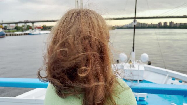 A woman stands thoughtfully on a cruise ship deck. Her hair blows softly in the breeze as she gazes across the Neva River. The calm journey brings a serene feeling of freedom.
