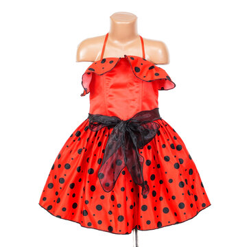 Vibrant red girls party dress with black polka dots, a ruffled neckline and sheer black waist sash displayed on a child mannequin against a clean white background
