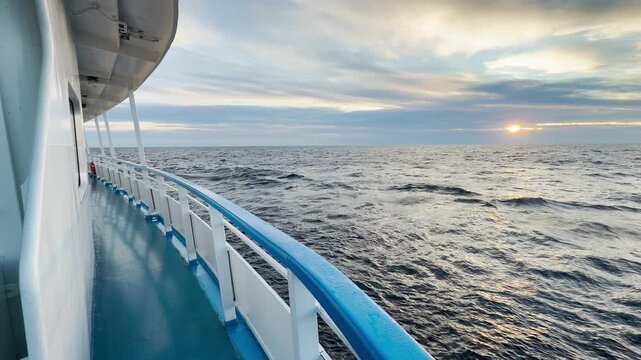 A cruise ship sails smoothly across Lake Ladoga at sunset. The glowing sun reflects on the gentle waves. This peaceful view brings a feeling of deep calm and joy.