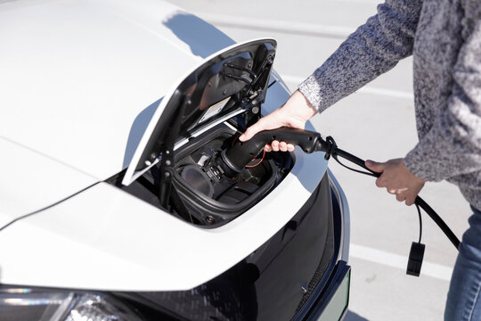 Data Set Training &ndash; woman charging electric car with EV charging station. Parking area background, providing a realistic everyday environment for electric vehicle charging.