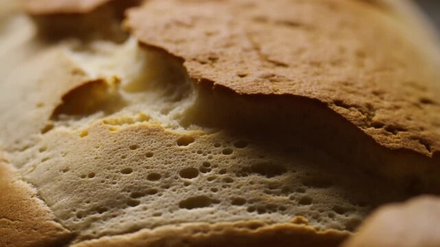 Freshly baked bread loaf with golden crust and porous crumb in warm indoor light. Bakery advertising, bread packaging, and baking tutorials.