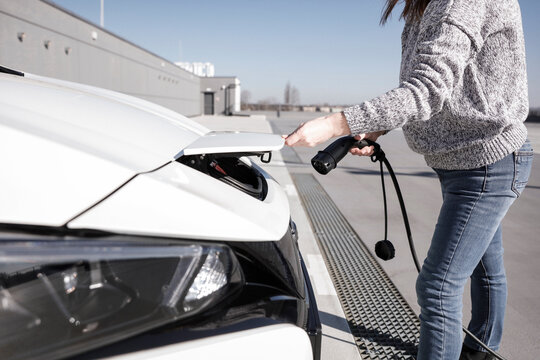 Data Set Training &ndash; woman charging electric car with EV charging station. Parking area background, providing a realistic everyday environment for electric vehicle charging.