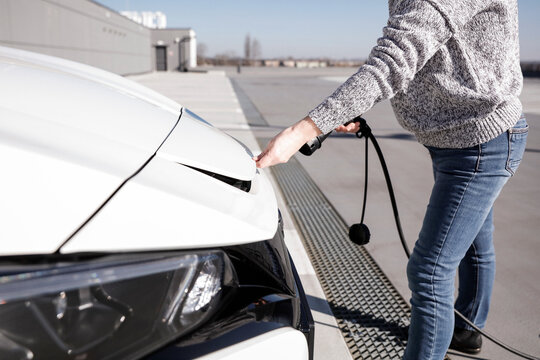 Data Set Training &ndash; woman charging electric car with EV charging station. Parking area background, providing a realistic everyday environment for electric vehicle charging.