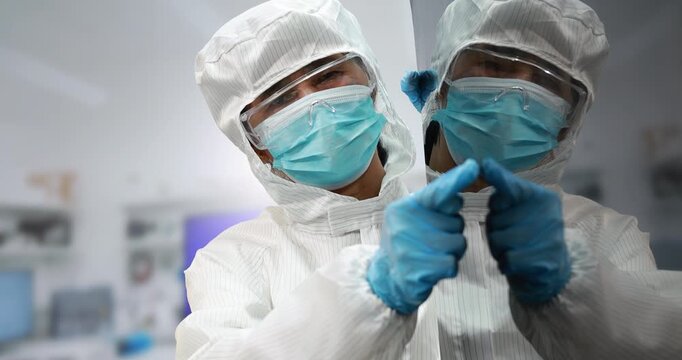 Technician in repair clothing and blue gloves carefully holds a large black display panel during electronics inspection or manufacturing.
