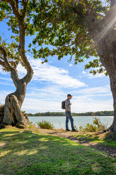 Man with Backpack Standing by a Lake or Coast