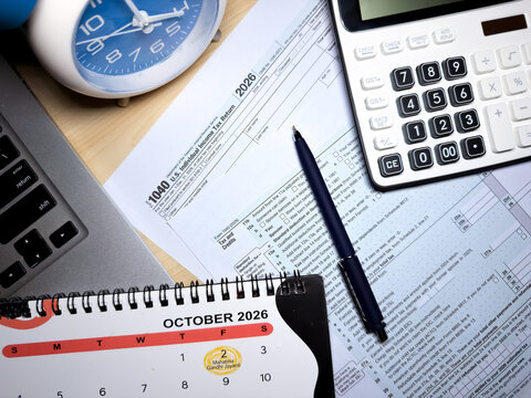 US tax return form 1040 with October 2026 calendar and calculator on office desk