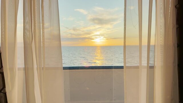 Soft curtains frame a setting sun over gentle waters on a cruise ship. The golden light creates a peaceful and cozy mood across Lake Ladoga.
