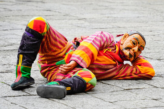 Drubchen festival, Dromchoe festival, mask dancing, Thimphu Dzong, Colorful traditional mask performer lying on stone pavement in vibrant costume, Thimphu, Bhutan, SEP 2026
