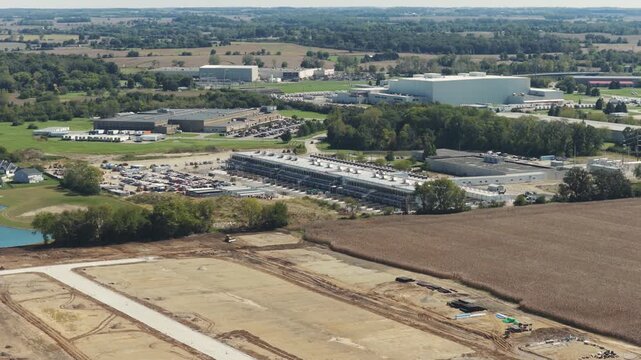 Drone aerial establishing view of large white data center construction being built in central Ohio by Springfield, OH near countryside rural country landscape of tech data building for AI hardware 4k