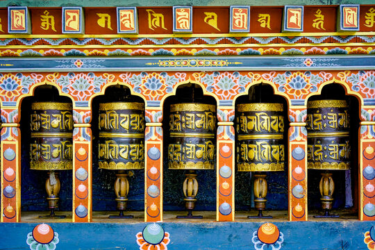Changangkha Lhakhang, Colorful row of traditional golden prayer wheels set in ornate temple wall