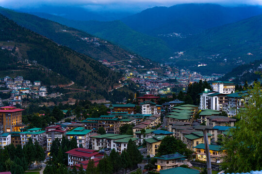 City view of Thimphu, Bhutan, Viewpoint on SEP 2026, Scenic mountain town at dusk with illuminated buildings and forest hills, sustainability, zero carbon, negative carbon