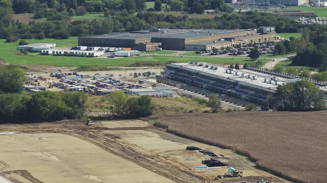 Drone aerial establishing view of large white data center construction being built in central Ohio by Springfield, OH near countryside rural country landscape of tech data building for AI hardware 4k