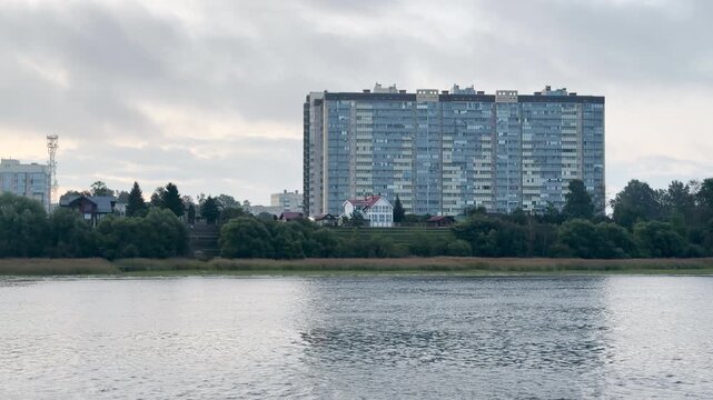 A cruise ship glides past tall apartment buildings along the Neva River shore. The calm waters create a peaceful, serene scene. The quiet view fills travelers with relaxing harmony.