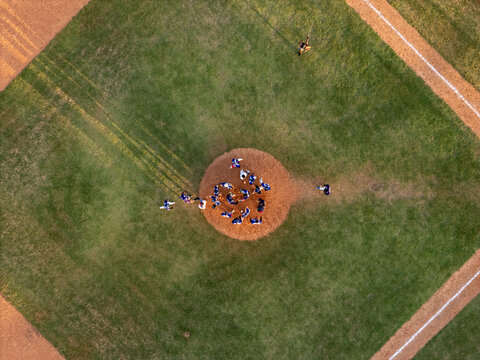 Aerial view of a baseball game in progress on a dirt mound and green grass field in Santo Domingo, Distrito Nacional, Dominican Republic.