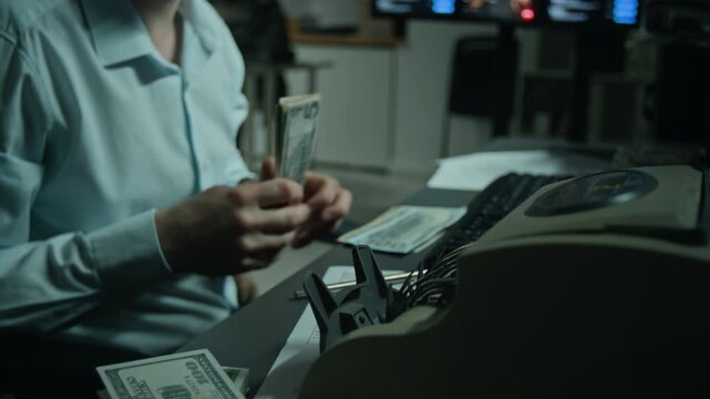 Unrecognizable man counting US dollar banknotes with electronic counter machine at desk. Ideal clip for banking, financial crime, money laundering, or investment videos