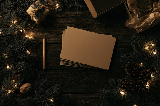 Blank kraft paper mockup with Christmas fir branches, lights, pencil, and box