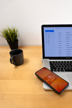 Laptop and smartphone showing unusual login security alert on wooden desk