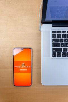 Smartphone with unusual login detected warning on wooden desk