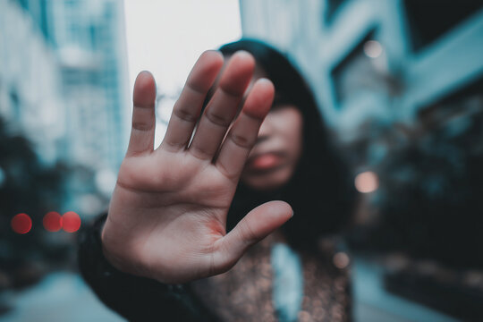 Woman holding her open palm toward the camera in a gesture of refusal, privacy, personal boundaries and protection.
