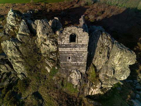 Aerial view of the historic Roche Rock stone chapel perched on a rugged granite outcrop surrounded by moorland in Roche, Cornwall, United Kingdom.