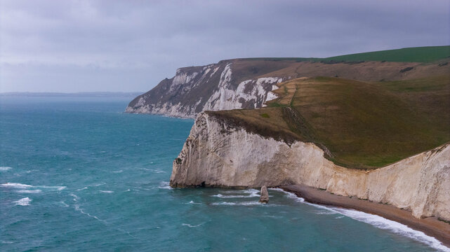 Aerial view of the iconic limestone arch of Durdle Door set against the dramatic chalk cliffs and turquoise waters of the Jurassic Coast in Wareham, England, United Kingdom.
